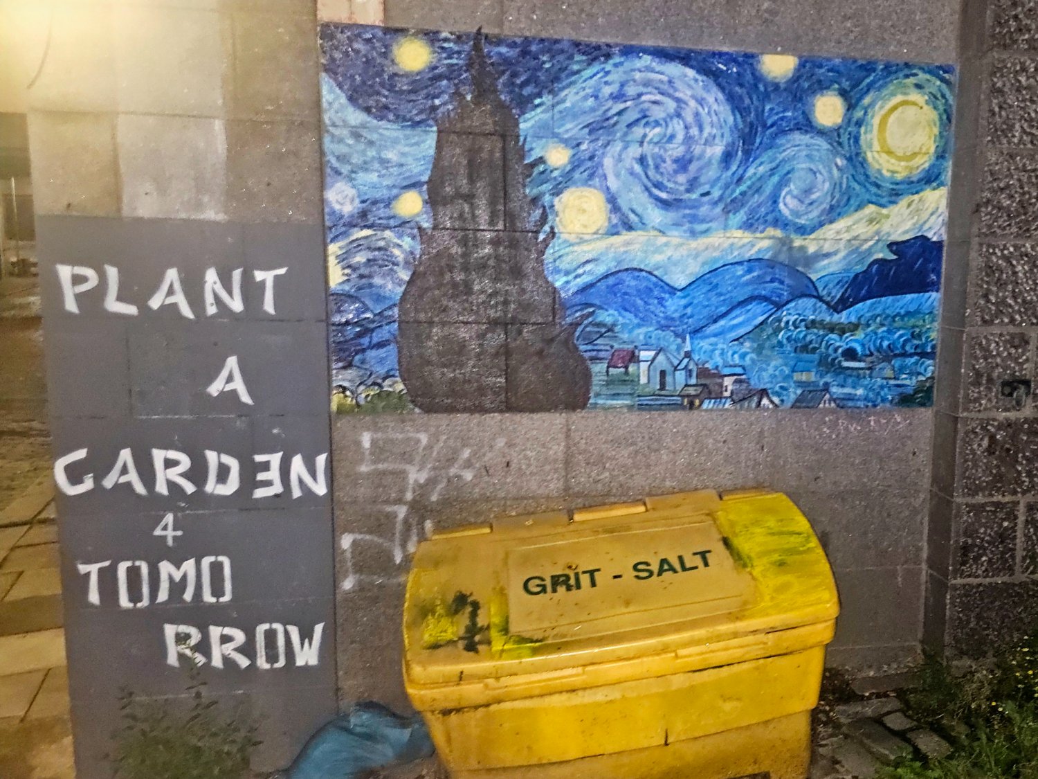 A Van Gogh Starry Night style mural with the words Plant A Garden 4 Tomorrow to the left of it and a large yellow grit bin underneath