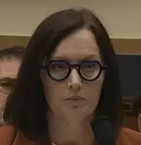 Dr Rauwens wearing thick rimmed glasses. They are round save for the top, which is flat. They are reminiscent of a scowling or frowning expression.