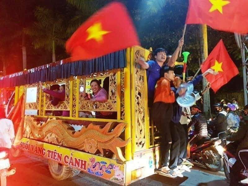 Youth waving Vietnamese flag on the back of antique-style tourism van